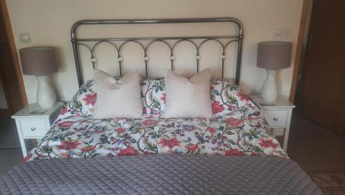 a bed with three pillows on it with two lamps at 2 Mill Cottages in Cornworthy