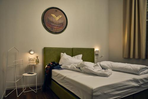 a bed with a green headboard and a clock on the wall at Hotel Paradiso Conca d'Oro in Nago-Torbole