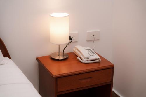 a lamp and a phone on a wooden table next to a bed at Rio Cumbaza Hotel in Tarapoto