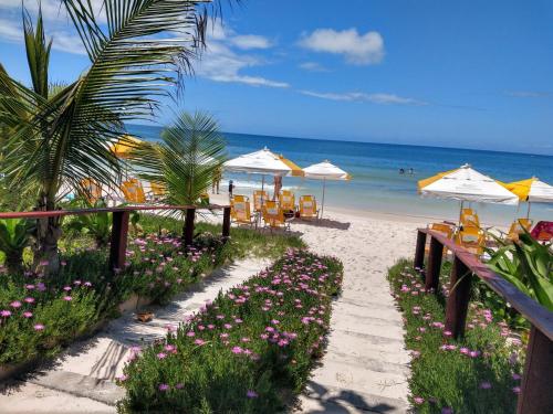 a beach with umbrellas and chairs and the ocean at Pousada Bella Bombinhas - Pé na areia in Bombinhas