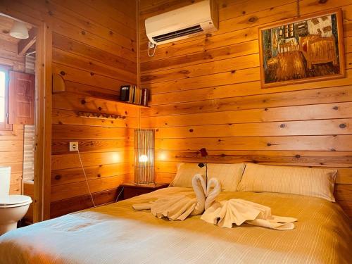 1 dormitorio con paredes de madera y 1 cama con toallas. en Cabañas El Descansito, en Chillarón de Cuenca