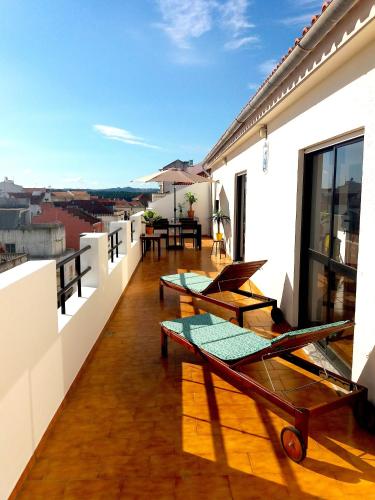 a balcony with tables and chairs on a building at Penthouse Apartment, City Center in Caldas da Rainha