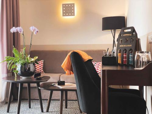 a living room with a couch and two tables with wine bottles at Best Western Plus La Corniche in Toulon