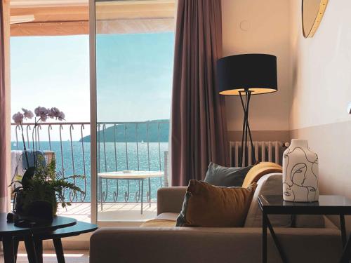 een woonkamer met een bank en uitzicht op de oceaan bij Best Western Plus La Corniche in Toulon