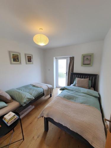 a bedroom with two beds and a window at Beautiful 2 bedroom guest house with private pool in Lacock, Wiltshire in Lacock