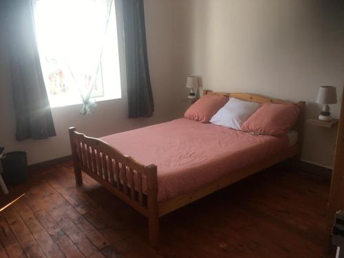 una camera da letto con un letto con lenzuola rosa e una finestra di Logement détente avec jacuzzi et billard américain a Fournols