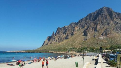 un grupo de personas en una playa con una montaña en Cofano Home, en Custonaci