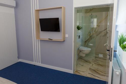 a bathroom with a toilet and a television on a wall at Hotel Quattro in Szczecinek