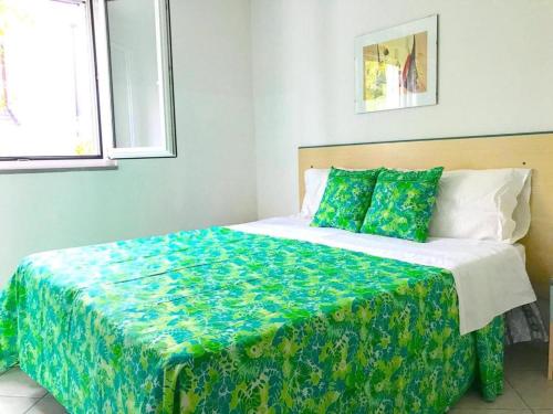 a bedroom with a large bed with a green blanket at Villaggio Calipso in Calopezzati