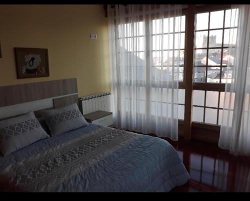 a bedroom with a bed and a large window at A casa do clarete in Castro Caldelas