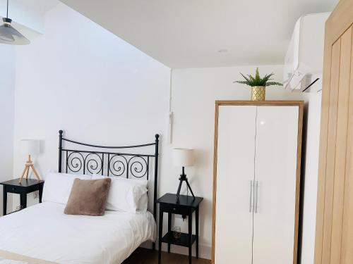 1 dormitorio con 1 cama con sábanas blancas y espejo en Exeter city centre entire house with parking, en Exeter