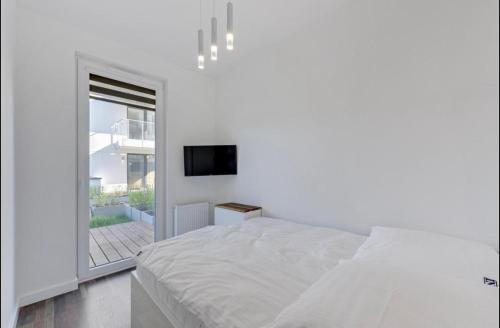 een witte slaapkamer met een bed en een raam bij SEA APART in Gdańsk