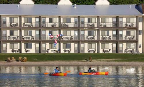 two people in kayaks in the water in front of a building at Bavarian Haus Lakefront Inn in Saint Ignace