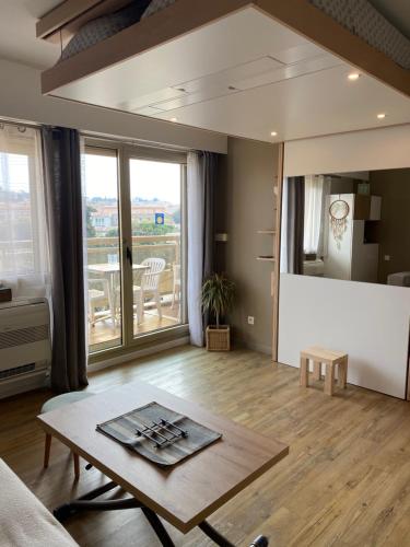 d'un salon avec une table et un balcon. dans l'établissement Le Petit mouchoir et son garage, à Sainte-Maxime