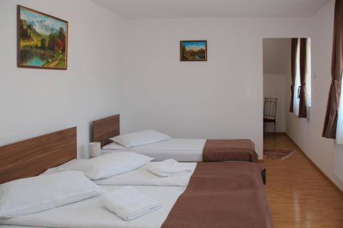 two beds in a room with white walls at Apartamente Gergely Apartmanok in Praid