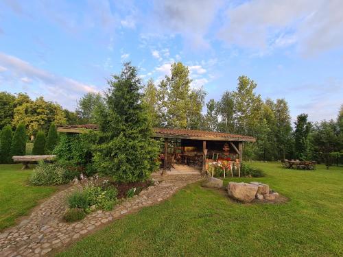 a pavilion in a field with a tree in the yard at Agroturystyka „Między Polami” in Zalewo