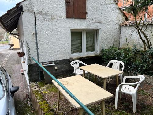 two tables and white chairs in front of a building at kleines Häuschen in Alzenau in Unterfranken