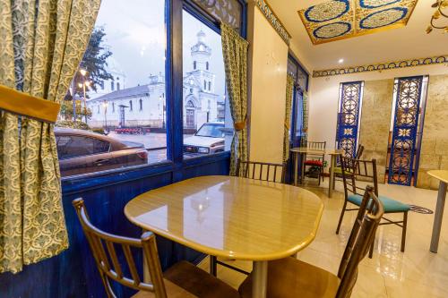 a table and chairs in a room with a window at Hotel Azul de la Plaza by Chat Noir in Cuenca