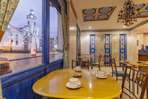 a table in a restaurant with a view of a church at Hotel Azul de la Plaza by Chat Noir in Cuenca