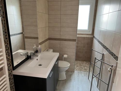 een badkamer met een wastafel, een toilet en een raam bij Villa Louizanne in Saint-Georges-de-Didonne