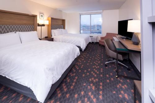 a hotel room with two beds and a desk at Holiday Inn Hotel & Suites Ann Arbor University of Michigan Area by IHG in Ann Arbor