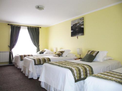 Habitación de hotel con 3 camas y ventana en Hotel Carpa Manzano, en Punta Arenas