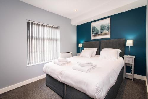 ein Schlafzimmer mit einem großen Bett mit blauer Wand in der Unterkunft Arena Apartments - Stylish and Homely Apartments by the Ice Arena with Parking in Nottingham