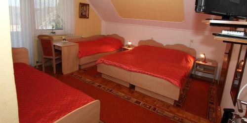 a bedroom with two beds with red sheets and a desk at Rooms & Apartments Jana in Cerklje na Gorenjskem
