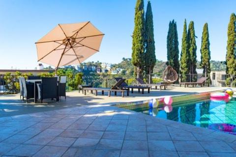 a pool with a table and an umbrella next to it at Hollywood Hills private room in Los Angeles