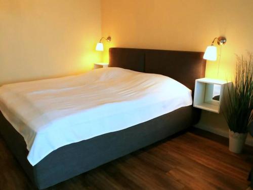 a large bed in a bedroom with two lamps and a plant at Fehmarn Burgtiefe Südstrand Meerblick Apartment MEERZEIT in Fehmarn