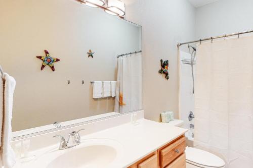 een badkamer met een wastafel, een toilet en een spiegel bij Ohana KDH122 in Kill Devil Hills