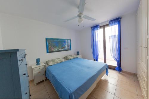 um quarto com uma cama azul e uma janela em Villa Maldive del Salento em Marina di Pescoluse