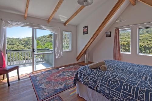 a bedroom with a bed and a balcony at Frosty's Retreat - Great Barrier Island Home in Tryphena