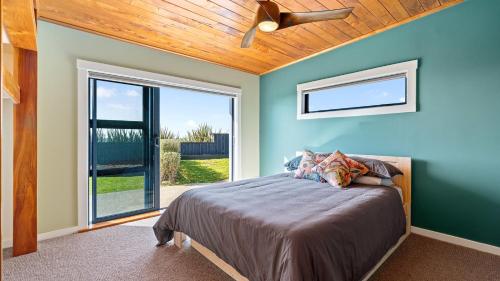 a bedroom with a bed with a ceiling fan at Coastal Daze - New Plymouth Holiday Home in Okato