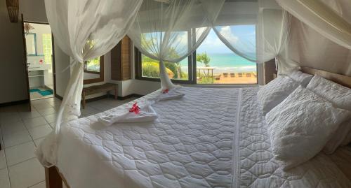 a bedroom with a white bed with a large window at Casa Buena Vista in Arraial d'Ajuda