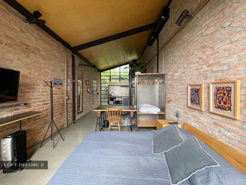 een slaapkamer met een bed en een bakstenen muur bij Degar Studios in Sao Paulo