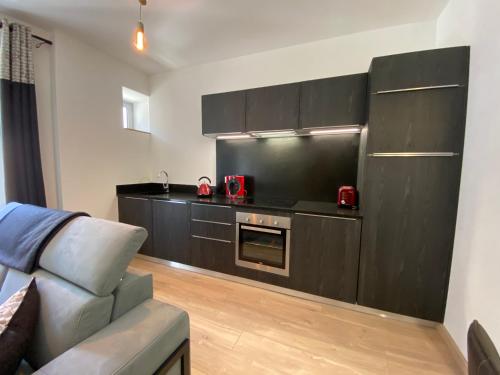 - une cuisine avec des armoires noires et un canapé dans la chambre dans l'établissement Plein centre, T3 5P totalement rénové 55m2. WIFI, à Cauterets