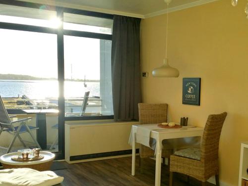 a dining room with a table and a view of a boat at Fehmarn Burgtiefe Südstrand Meerblick Apartment MEERZEIT in Fehmarn