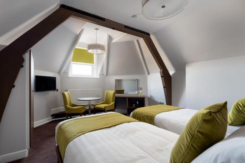 a room with two beds and a table and chairs at St Andrews Hotel in Exeter