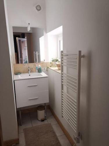 une salle de bain blanche avec un lavabo et un miroir dans l'établissement Maison Colette au coeur du périgord noir, à Montignac