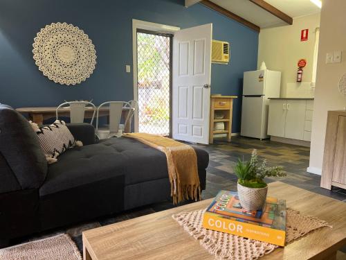 a living room with a black couch and a kitchen at Colonial Village Resort in Hervey Bay