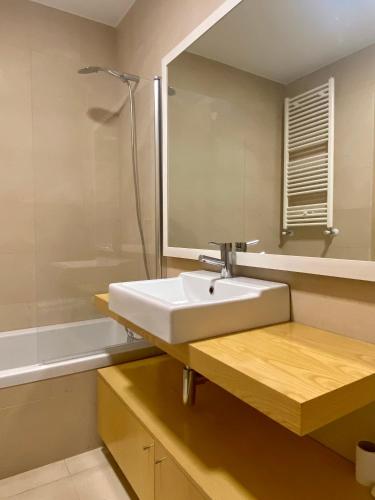 a bathroom with a sink and a mirror and a tub at Apartamento O Albuquerque - Centro Cidade Alcobaça in Alcobaça