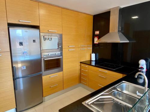 una cucina con armadi in legno e frigorifero in acciaio inossidabile di Apartamento O Albuquerque - Centro Cidade Alcobaça ad Alcobaça