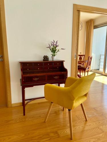 a yellow chair in a living room with a desk at Apartamento O Albuquerque - Centro Cidade Alcobaça in Alcobaça