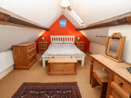 um quarto no sótão com uma cama e mobiliário em madeira em Bwthyn Celyn Holly Cottage em Llannor