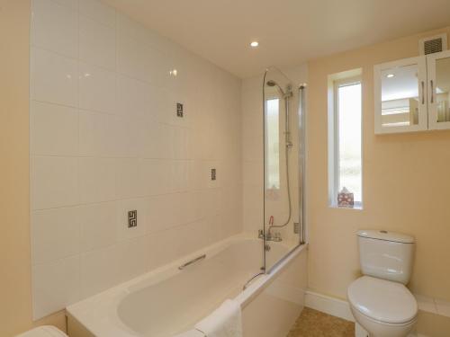 a white bathroom with a tub and a toilet at Clock Tower Cottage in Great Bedwyn