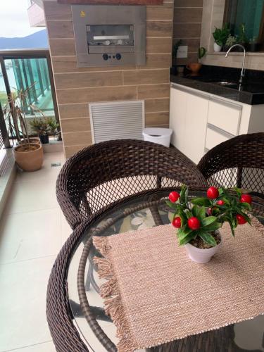 a balcony with a table and chairs with a plant on it at apartamento de frente para o mar com linda area de lazer in Arraial do Cabo