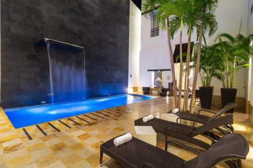 a swimming pool in a room with chairs and a table at Hotel Republicano 1910 in Girardot
