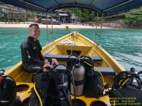 a man sitting in a boat on the water at Perhentian Chomel Chalet in Perhentian Island