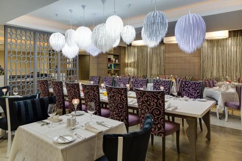 a restaurant with white tables and purple chairs and chandeliers at ANEW Hotel Hatfield Pretoria in Pretoria